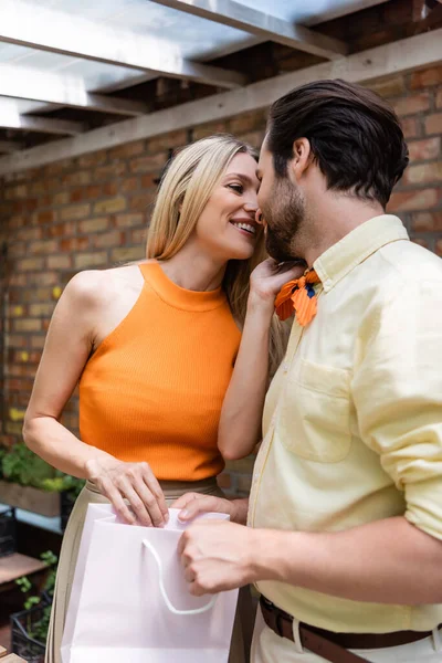 Mulher alegre beijando namorado com saco de compras no café ao ar livre — Fotografia de Stock