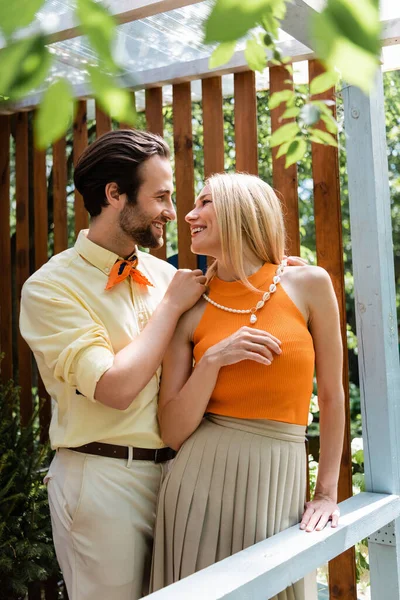Seitenansicht von stilvollen Mann trägt Halskette auf stilvolle Freundin auf der Terrasse des Cafés — Stockfoto