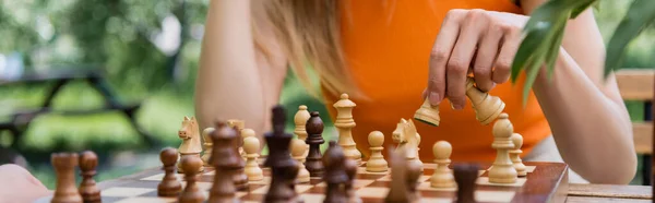 Vista cortada da mulher jogando xadrez desfocado no parque, banner — Fotografia de Stock