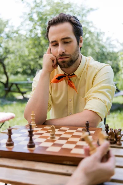 Thoughtful man looking at chess board near girlfriend in park — Stock Photo