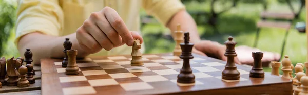 Ausgeschnittene Ansicht eines verschwommenen Mannes, der Schach im Park spielt, Banner — Stockfoto