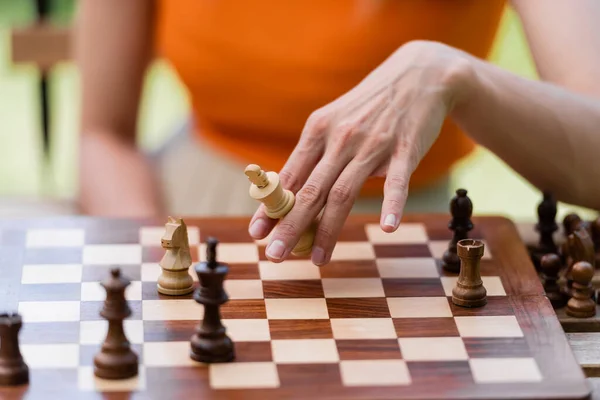 Ausgeschnittene Ansicht einer Frau mit Schachfigur in der Nähe eines Brettes im Park — Stockfoto