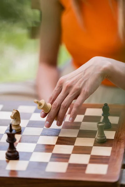 Vista recortada de una mujer sosteniendo figura de ajedrez cerca del tablero en el parque - foto de stock