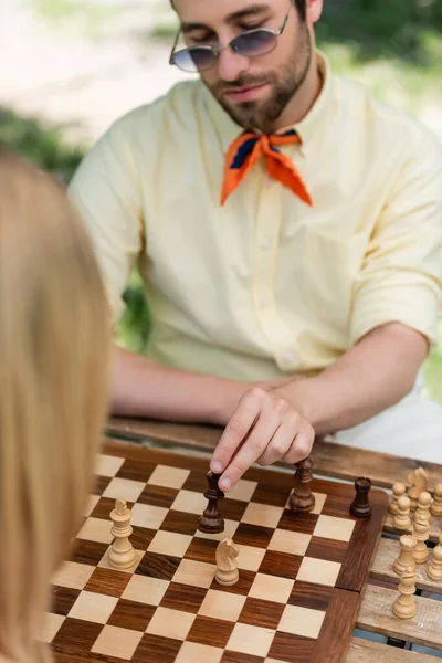 Homem elegante borrado jogando xadrez com mulher no parque — Fotografia de Stock