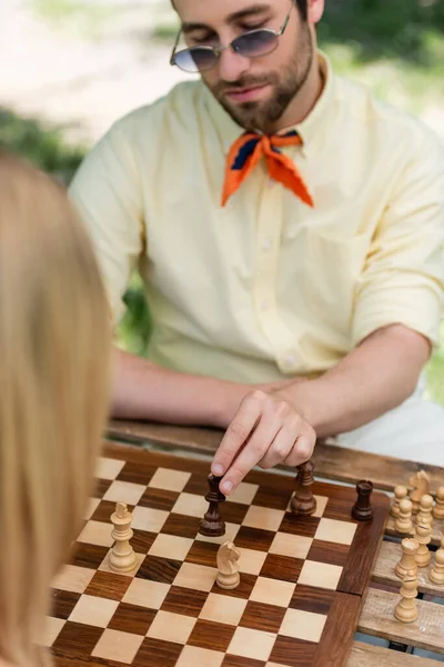 Blurred stylish man playing chess with woman in park — Stock Photo