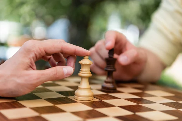 Vista cortada de mulher tocando figura de xadrez perto namorado no parque — Fotografia de Stock