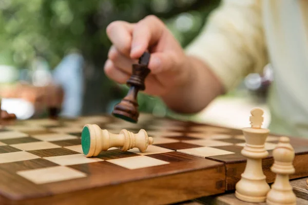 Cropped view of floured man holding chess figure near board à l'extérieur — Photo de stock