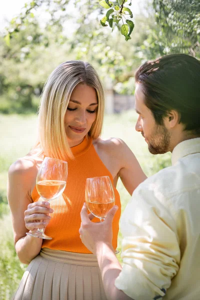 Stylish woman holding wine near boyfriend in summer park — Stock Photo