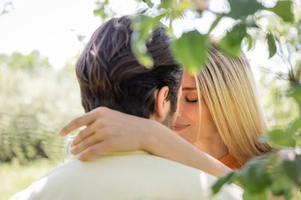 Mujer besándose y abrazando borrosa novio en verano parque - foto de stock