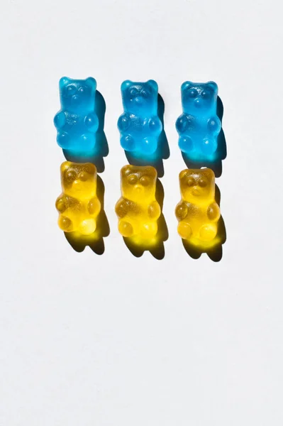 Draufsicht auf blaue und gelbe Gummibärchen auf weißem Hintergrund — Stockfoto