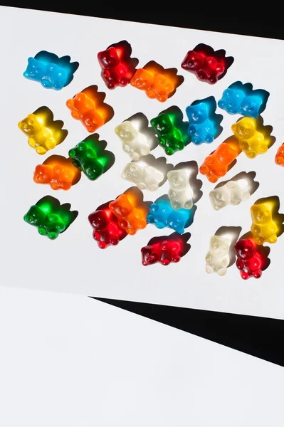Visão superior de ursos coloridos de goma no fundo branco e preto — Fotografia de Stock