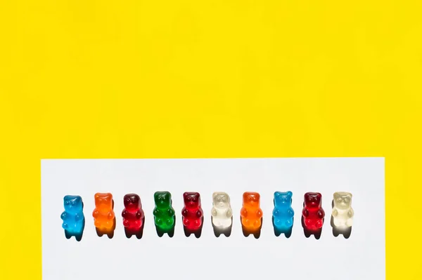 Top view of row from gummy bears on white and yellow — Stock Photo