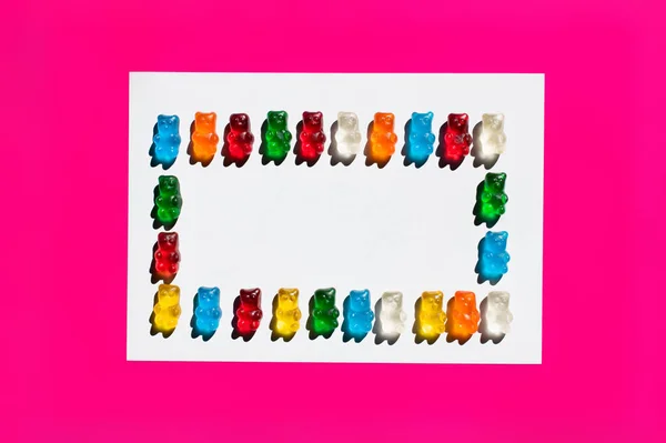 Flat lay with colorful gummy bears on white and pink surface — Stock Photo