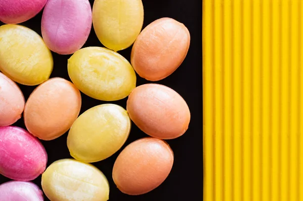 Vue du dessus des bonbons sucrés sur surface jaune texturée et noire — Photo de stock