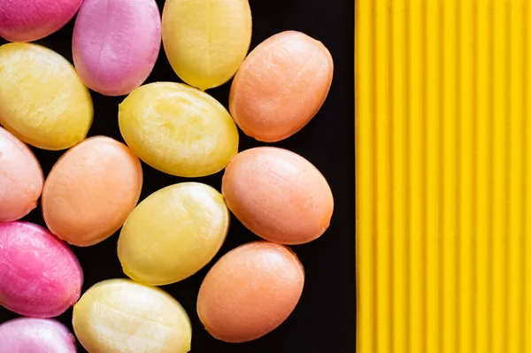 Top view of sweet candies on black and textured yellow surface — Stock Photo