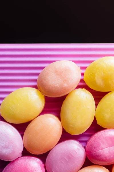 Close up view of candies on textured pink isolated on black — Stock Photo