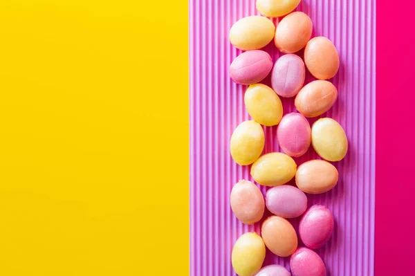 Flat lay with lollipops on textured pink and yellow surface — Stock Photo