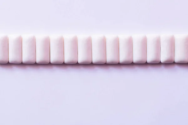 Pose plate avec rangée de gommes à mâcher sur fond blanc — Photo de stock