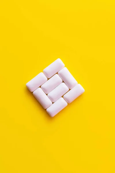 Flat lay of chewing gums in square shape on yellow background — Stock Photo