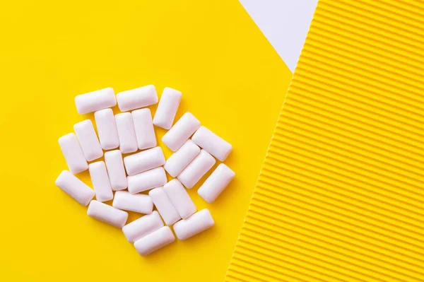 Vue du dessus des gencives blanches à mâcher sur fond jaune — Stock Photo