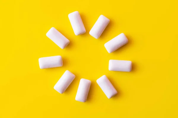 Flat lay of round shape from chewing gums on yellow background — Stock Photo