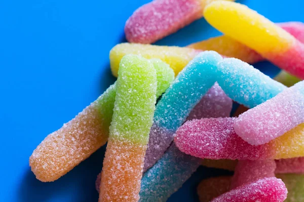 Nahaufnahme von Gummibonbons mit Zucker auf blauem Hintergrund — Stockfoto