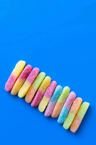 Acostado plano con dulces gomosos sobre fondo azul - foto de stock