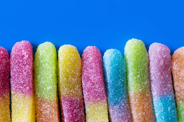 Close up view of gummy sweets with sugar on blue background — Stock Photo