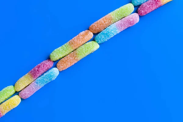 Acostado plano con dulces de gelatina con azúcar sobre fondo azul - foto de stock