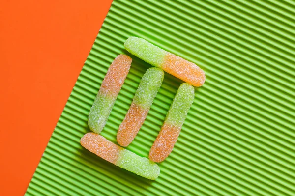 Flat lay with delicious jelly sweets on textured green and orange surface — Stock Photo