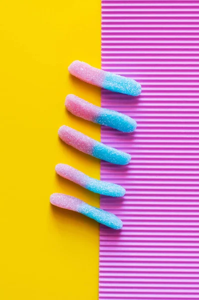 Flat lay with colorful jelly sweets on pink and yellow background — Stock Photo