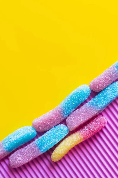 Flat lay of colorful gummy sweets on pink and yellow background — Stock Photo