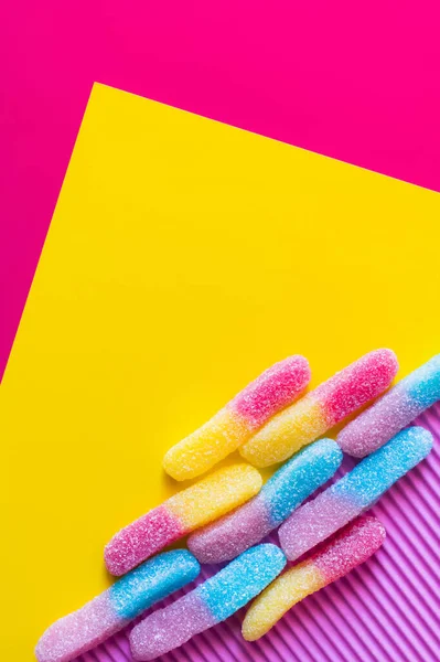 Posa piatta con caramelle alla gelatina con zucchero su sfondo rosa e giallo — Foto stock