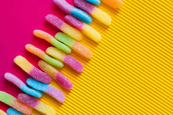 Flat lay with gummy sweets on pink and textured yellow surface — Stock Photo