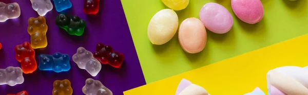 Colocação plana de ursos de goma perto de doces e marshmallows na superfície colorida, banner — Fotografia de Stock