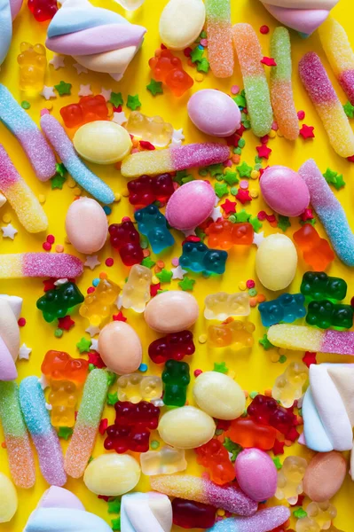 Vista dall'alto di marshmallow colorati e orsetti gommosi sulla superficie gialla — Foto stock