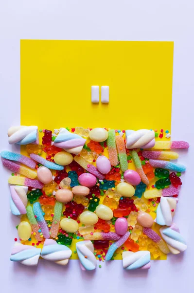 Top view of chewing gums near colorful sweets on white and yellow surface — Stock Photo