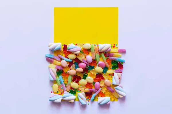 Top view of sweet candies and marshmallows on white and yellow surface — Stock Photo