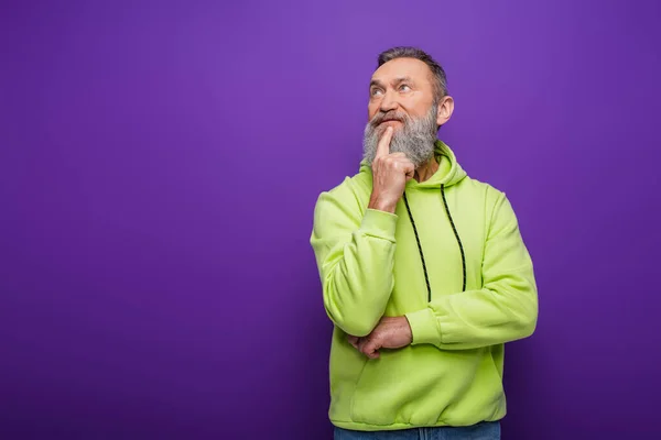 Nachdenklicher älterer Mann mit Bart und grauen Haaren schaut weg, während er an Lila denkt — Stockfoto