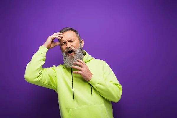 Hombre mayor con barba y pelo gris con dolor de cabeza sobre fondo púrpura - foto de stock