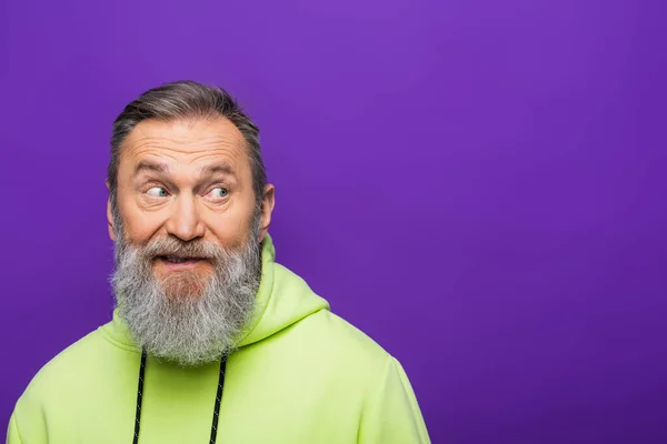 Homem sênior duvidoso com barba olhando para longe em roxo — Fotografia de Stock