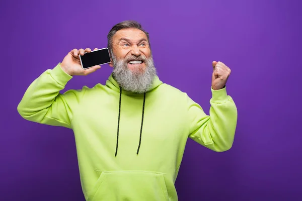 Homem sênior espantado segurando smartphone com tela em branco isolado em roxo — Fotografia de Stock