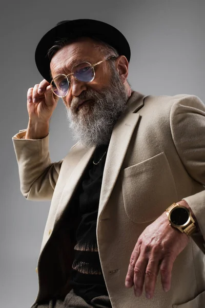 Portrait of bearded senior man in stylish beige jacket and derby hat on grey — Stock Photo