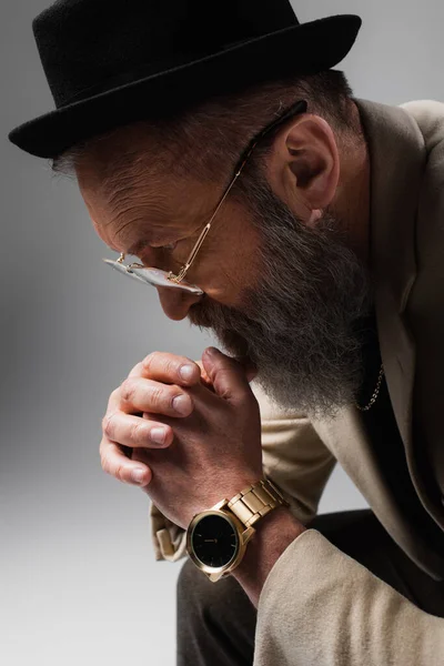 Portrait of pensive senior man in stylish beige jacket and derby hat on grey — Stock Photo