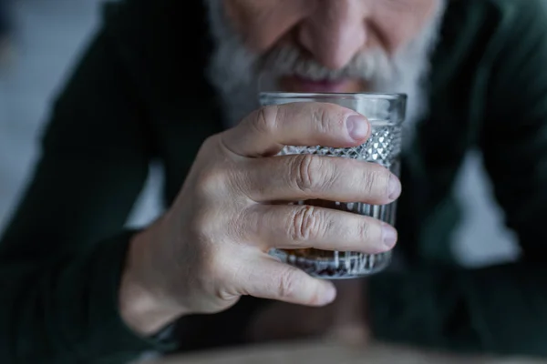 Cropped view of senior man drinking whiskey while holding glass — Stock Photo