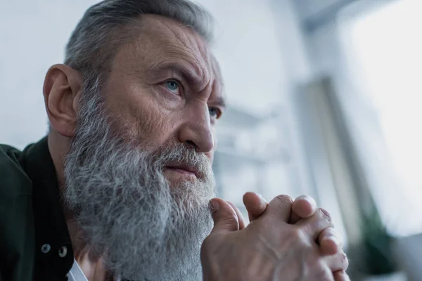 Portrait of sad senior man with wrinkles and clenched hands suffering crisis — Stock Photo