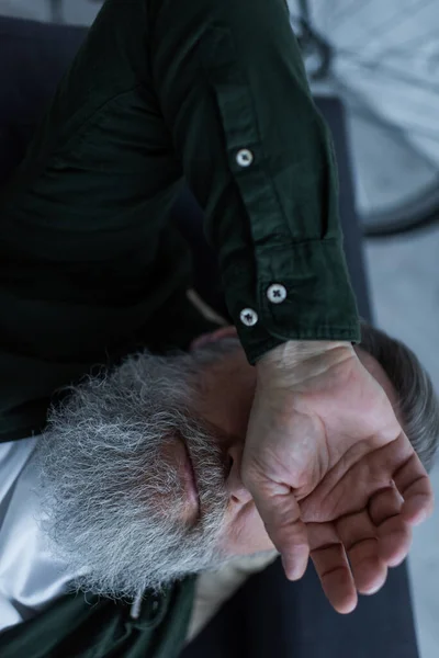 Вид зверху нещасного пенсіонера з бородою, що лежить на дивані під час кризи — стокове фото