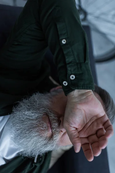 Top view of unhappy retired man with beard lying on couch while suffering crisis — Stock Photo