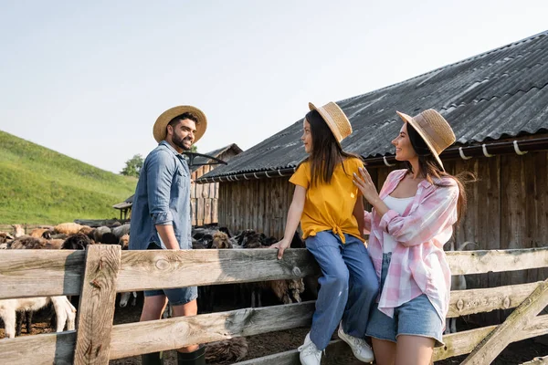 Girl in straw hat sitting on wooden fence near mom and dad in corral — Stock Photo