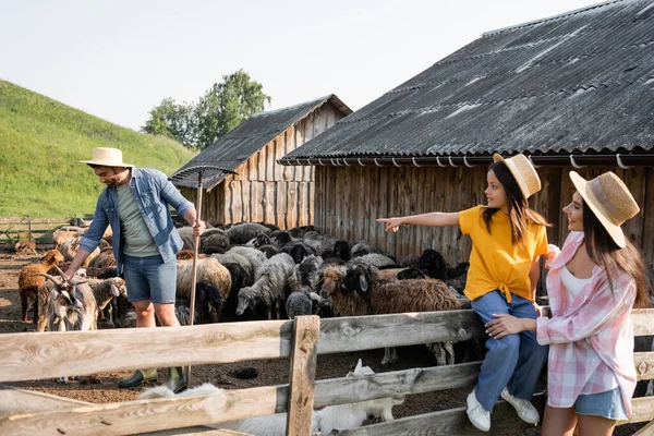 Happy woman smiling near girl pointing at dad working with cattle in corral — Fotografia de Stock